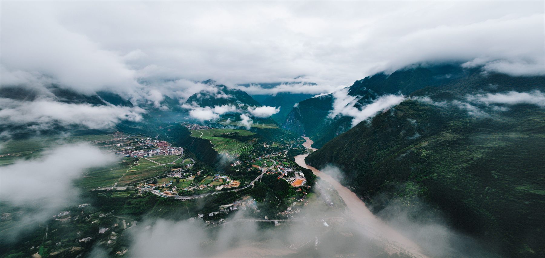 Aerial view of the river valley below the Gaoligong mountains in Yunnan, with cloud sitting low across the ridges